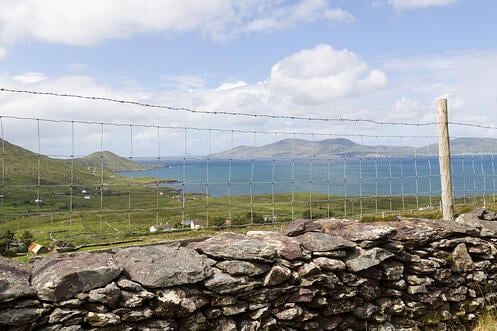 stone wall and wire fence in front of ocean