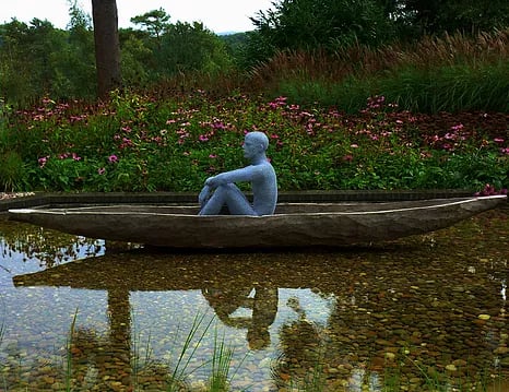 wire sculpture of man in wood canoe